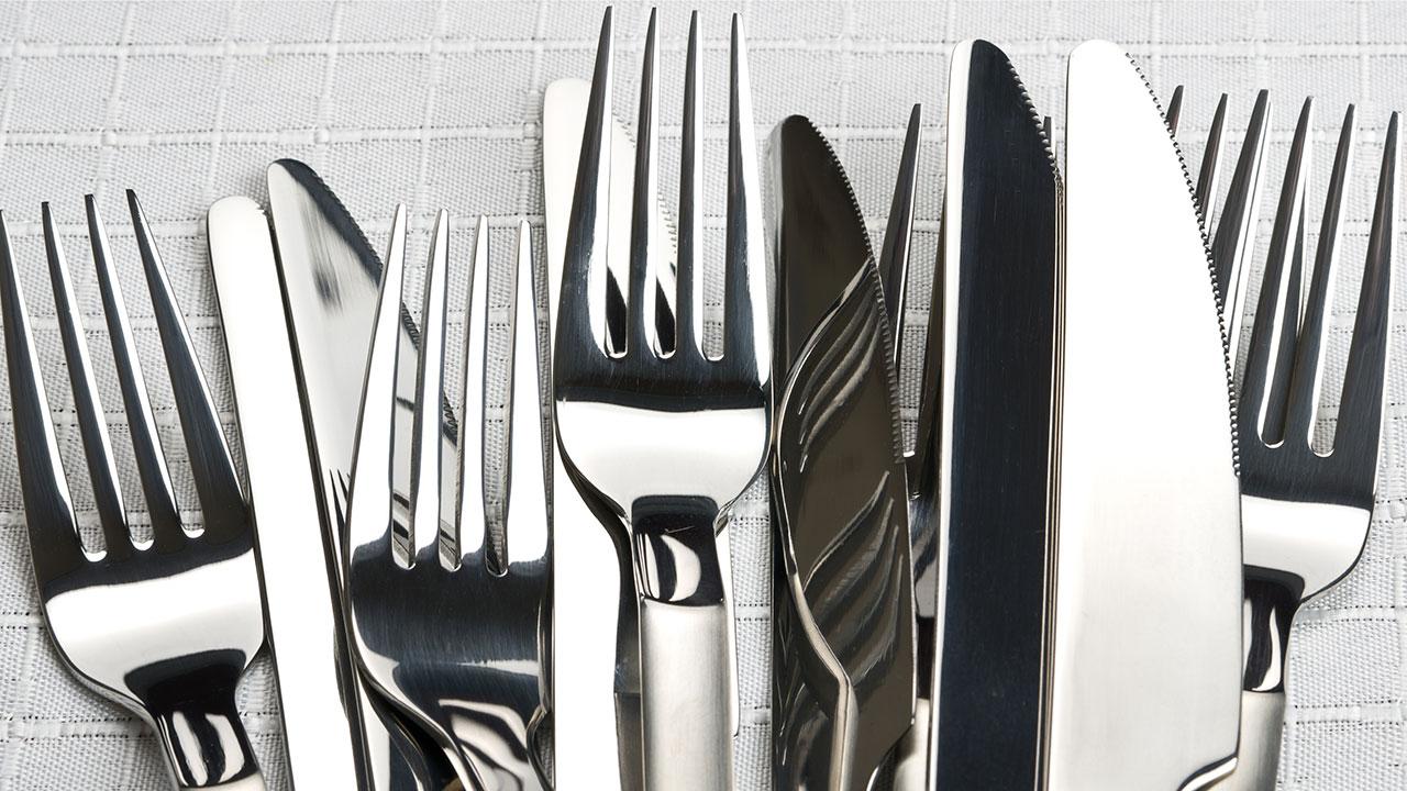 Skinnende knive og gafler i en bunke på et bord